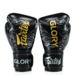 Black Fightgear KTM boxing gloves with gold “Fairtex” and “Glory” branding, featuring white swirl designs on the front and wrist straps.