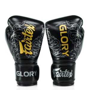 Black Fightgear KTM boxing gloves with gold “Fairtex” and “Glory” branding, featuring white swirl designs on the front and wrist straps.